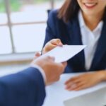 uomo allunga foglio a una ragazza