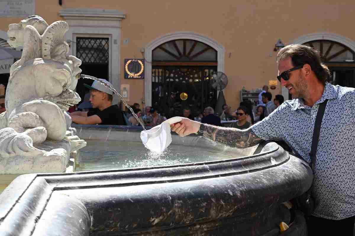 un uomo si rinfresca con l'acqua di una fontana