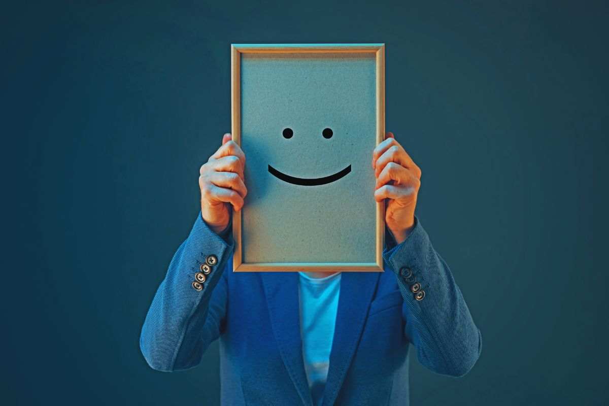 un uomo tiene in mano un cartello con una faccina sorridente