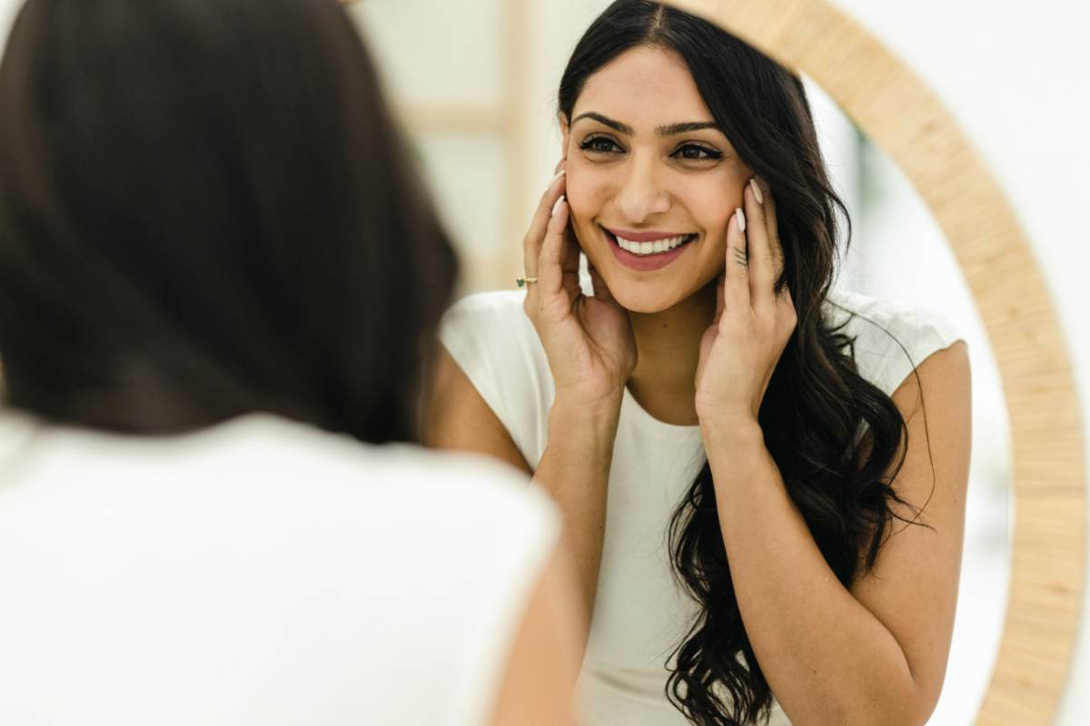Donna che si guarda allo specchio con il sorriso