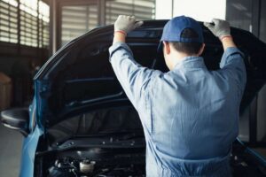 Persona che controlla l'interno del cofano di un'auto