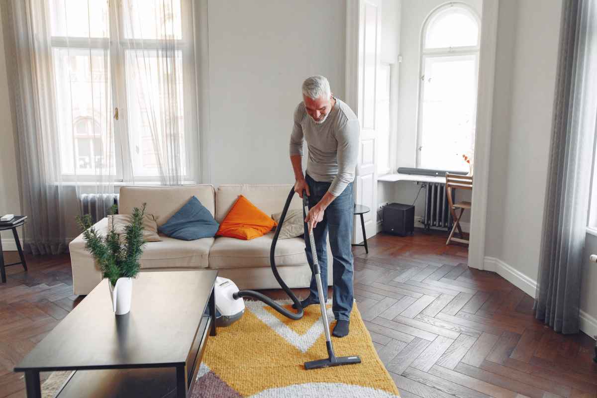 Uomo che passa aspirapolvere in soggiorno