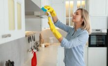 Donna che pulisce mobile della cucina