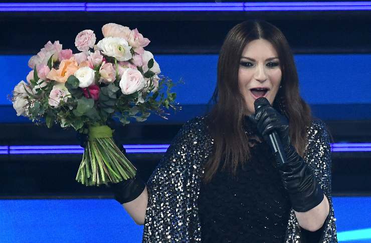 Laura Pausini con il microfono in mano e un bouquet di fiori