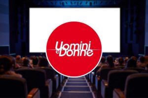 logo uomini e donne al centro e sala cinema come sfondo